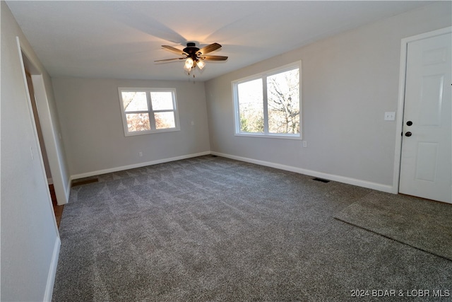 spare room with ceiling fan and dark carpet