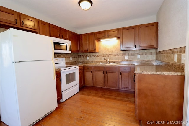 kitchen with light hardwood / wood-style floors, sink, white appliances, and backsplash