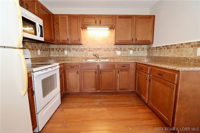 kitchen featuring decorative backsplash, light wood-type flooring, white appliances, and sink