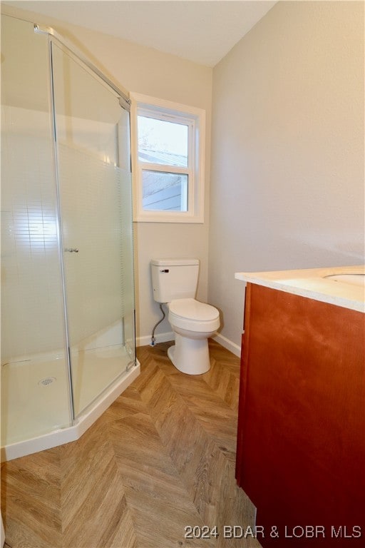 bathroom featuring vanity, parquet flooring, toilet, and a shower with door