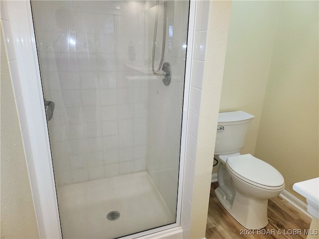 bathroom with walk in shower, toilet, and hardwood / wood-style flooring