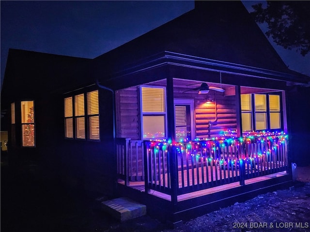 property exterior at twilight with ceiling fan and a deck