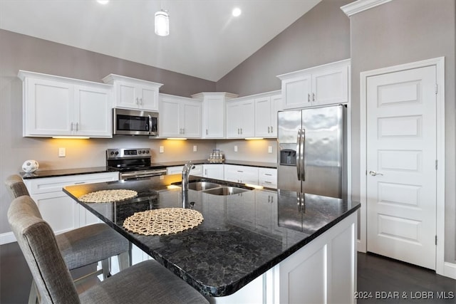 kitchen with a center island with sink, appliances with stainless steel finishes, sink, vaulted ceiling, and white cabinets