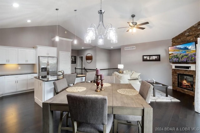 dining area featuring ceiling fan with notable chandelier, dark wood-type flooring, visible vents, and a fireplace