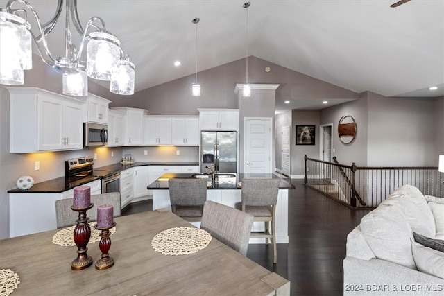 kitchen featuring stainless steel appliances, white cabinetry, an island with sink, pendant lighting, and dark hardwood / wood-style flooring