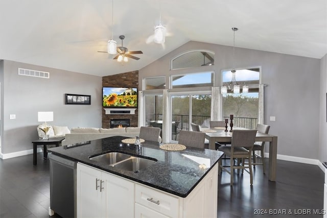 kitchen featuring a stone fireplace, lofted ceiling, white cabinets, dishwasher, and dark stone countertops