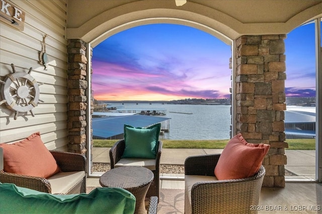 patio terrace at dusk featuring outdoor lounge area and a water view