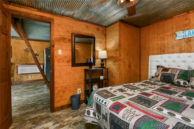 bedroom featuring dark wood-type flooring, a wall mounted AC, wooden walls, ceiling fan, and stainless steel refrigerator