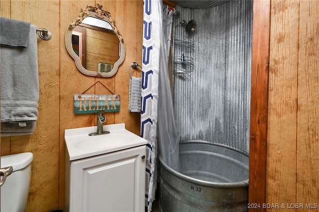 bathroom with vanity, wooden walls, and toilet