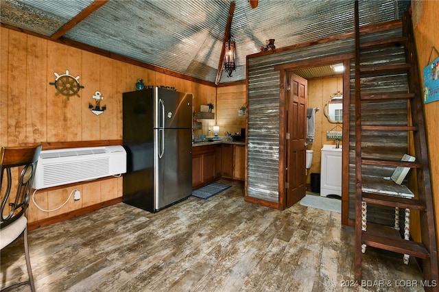 kitchen featuring stainless steel fridge, dark hardwood / wood-style flooring, wooden walls, vaulted ceiling, and a wall mounted air conditioner