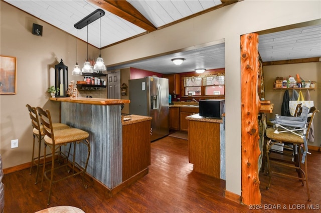 kitchen featuring a kitchen bar, vaulted ceiling, stainless steel refrigerator with ice dispenser, kitchen peninsula, and pendant lighting