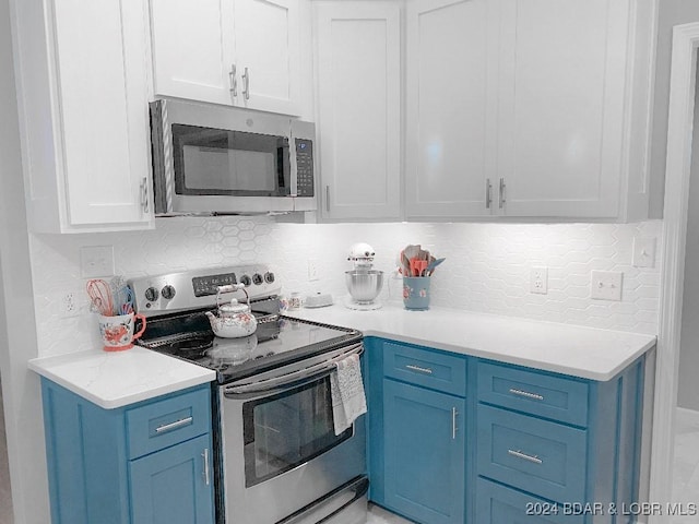 kitchen with white cabinetry, decorative backsplash, blue cabinetry, and appliances with stainless steel finishes