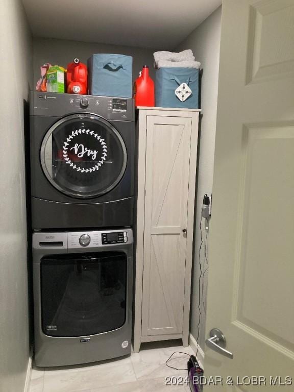 washroom with stacked washer and dryer and cabinets