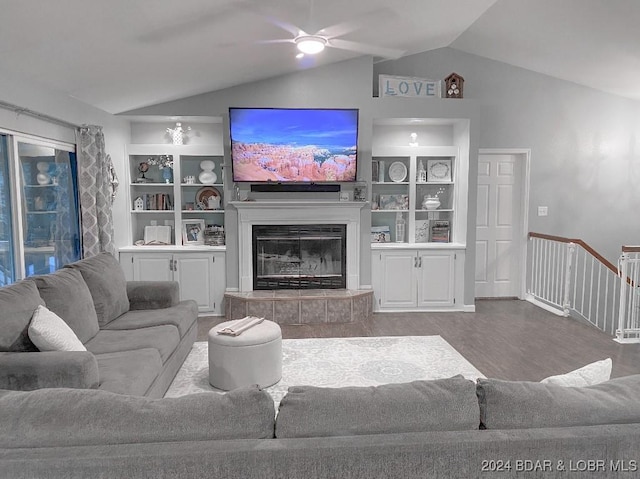 living room with lofted ceiling, built in shelves, ceiling fan, a fireplace, and wood-type flooring