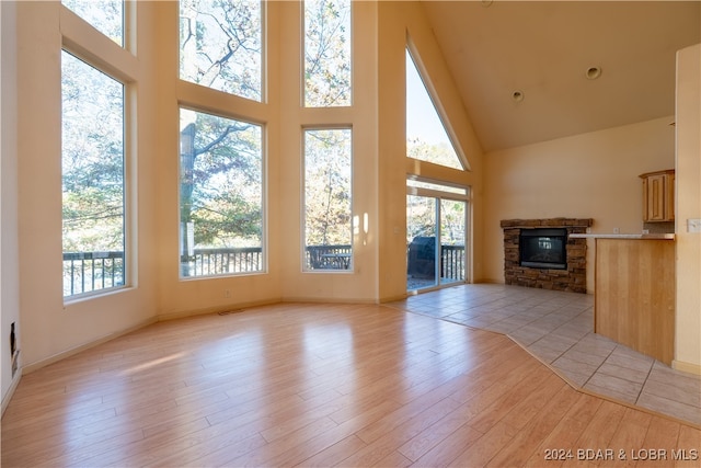 unfurnished living room with a high ceiling, light wood-type flooring, and plenty of natural light