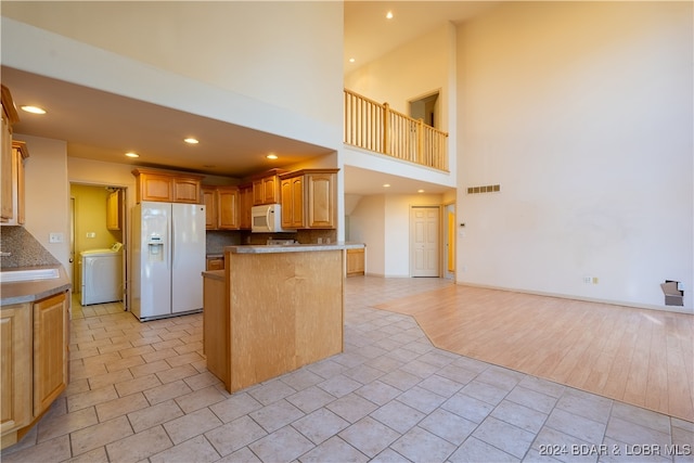 kitchen featuring washer / dryer, white appliances, decorative backsplash, kitchen peninsula, and light hardwood / wood-style flooring