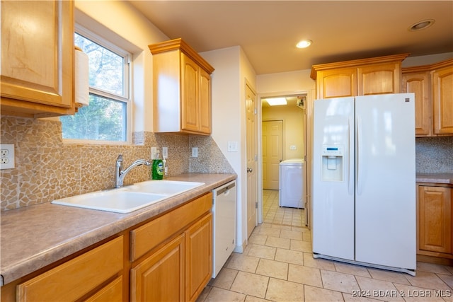 kitchen with washer / clothes dryer, backsplash, white appliances, and sink