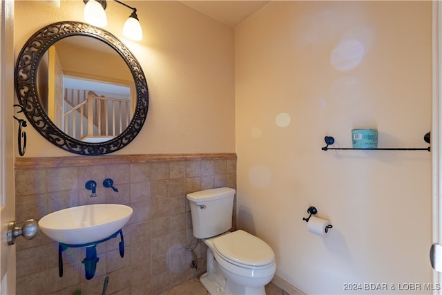 bathroom with toilet, tile walls, and sink