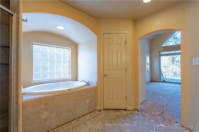 bathroom featuring a relaxing tiled tub and plenty of natural light