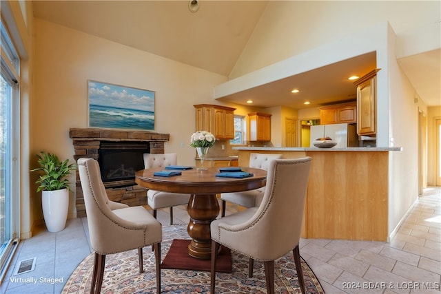 dining area featuring high vaulted ceiling and a fireplace