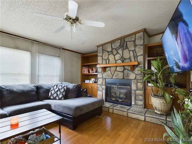 33467 Lakewood Shores Dr, Sunrise Beach, MO 65079 - living area featuring ornamental molding, a textured ceiling, wood finished floors, a stone fireplace, and a ceiling fan