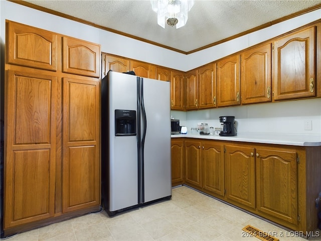 kitchen featuring stainless steel refrigerator with ice dispenser, ornamental molding, and a textured ceiling