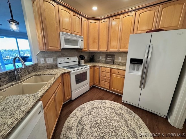 kitchen featuring white appliances, decorative light fixtures, light stone counters, and sink