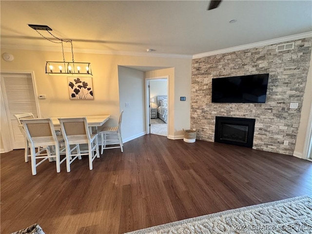 dining area with ornamental molding, dark hardwood / wood-style floors, a chandelier, and a stone fireplace