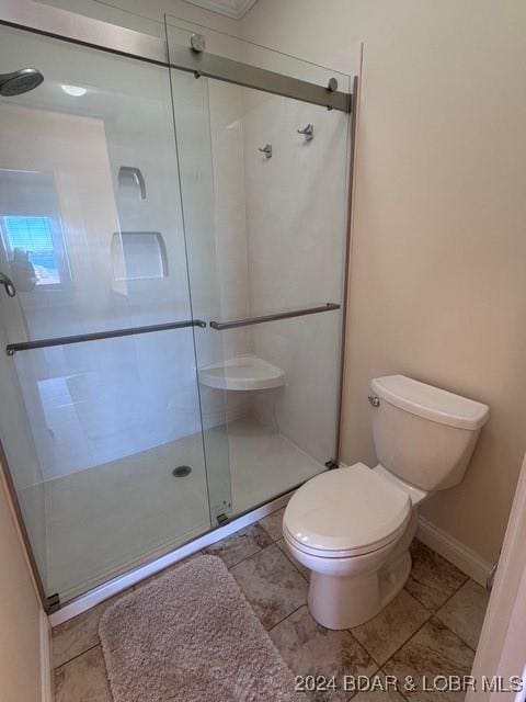 bathroom featuring toilet and a shower with shower door