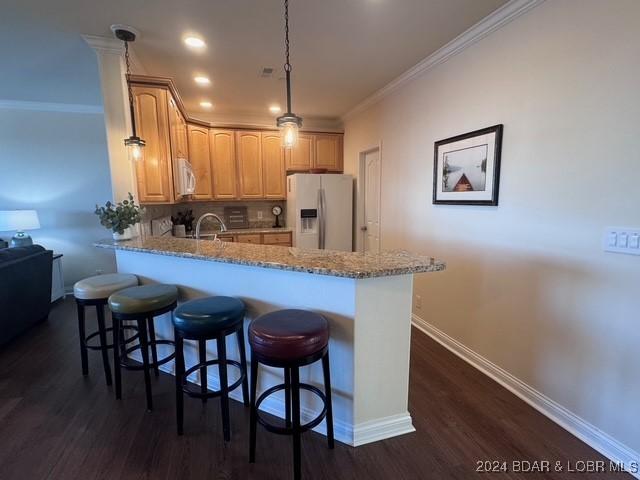 kitchen with decorative light fixtures, white appliances, ornamental molding, kitchen peninsula, and light stone countertops