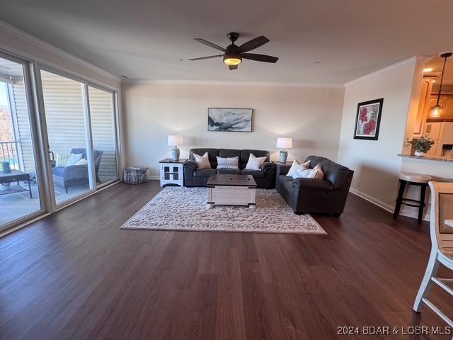 living room featuring dark wood-type flooring, ceiling fan, and crown molding