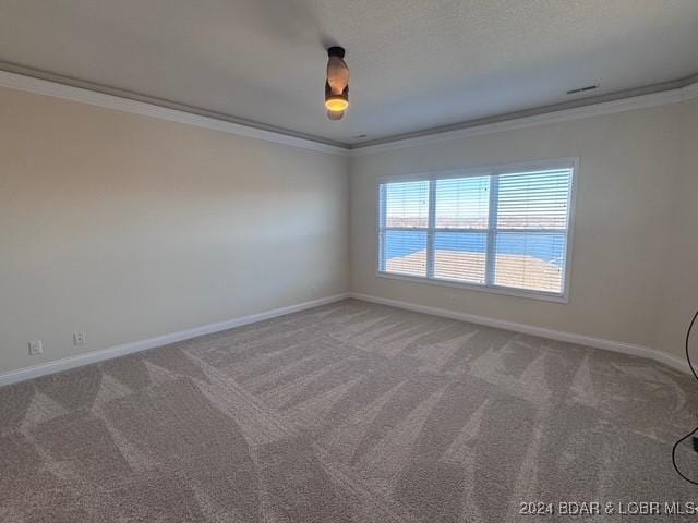 spare room with ornamental molding, a water view, and carpet