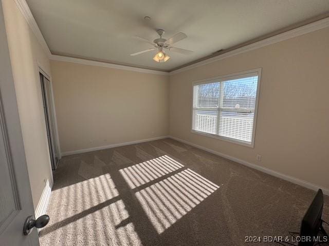 carpeted empty room with ceiling fan and crown molding