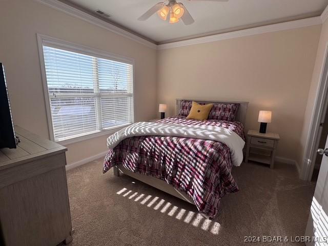 bedroom featuring ceiling fan, ornamental molding, and dark carpet