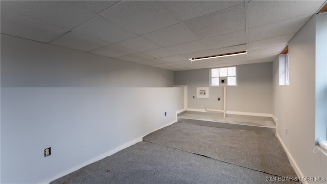 basement with a drop ceiling, carpet flooring, and baseboards