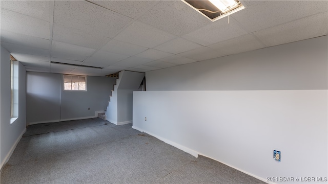 basement featuring carpet floors, a paneled ceiling, and baseboards