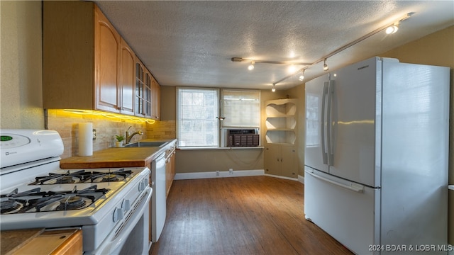 kitchen with white appliances, tasteful backsplash, hardwood / wood-style floors, a textured ceiling, and a sink