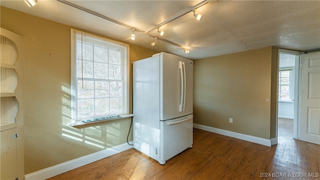 kitchen with a healthy amount of sunlight, white fridge, wood-type flooring, and rail lighting