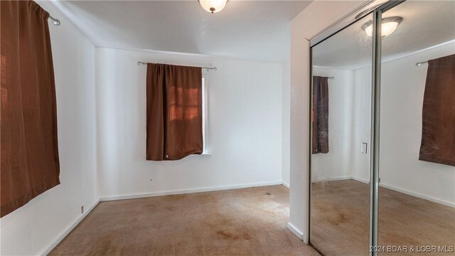 unfurnished bedroom with carpet floors, a closet, and baseboards