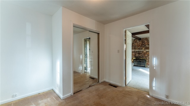 hallway featuring beam ceiling and light colored carpet