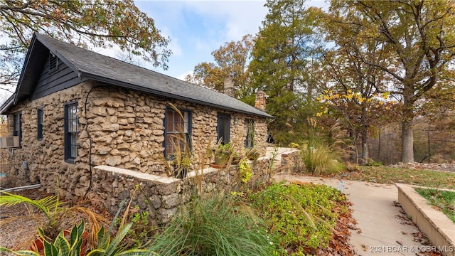 view of side of home with stone siding and a chimney