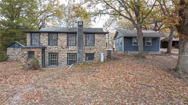 rear view of property with a chimney and central air condition unit