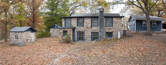 back of property featuring an outbuilding, stone siding, and central AC