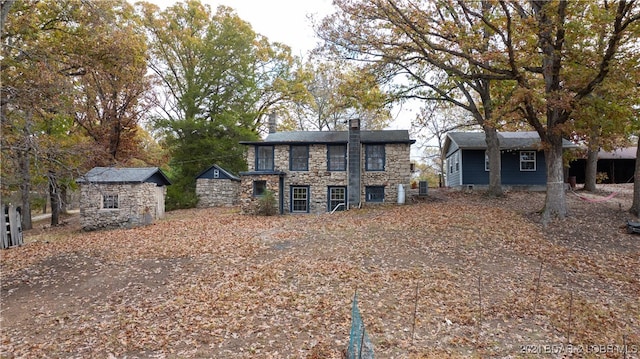 view of front of property featuring stone siding, a storage unit, and an outdoor structure