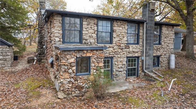 view of home's exterior with stone siding and a chimney