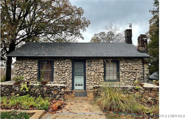 view of front facade featuring stone siding and a chimney