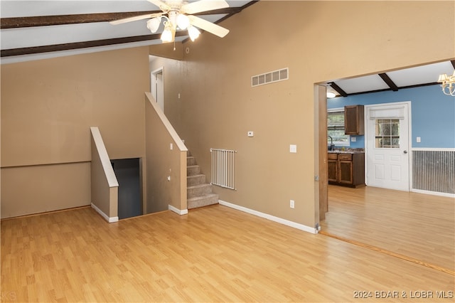 unfurnished living room with light wood-type flooring, vaulted ceiling with beams, and ceiling fan with notable chandelier