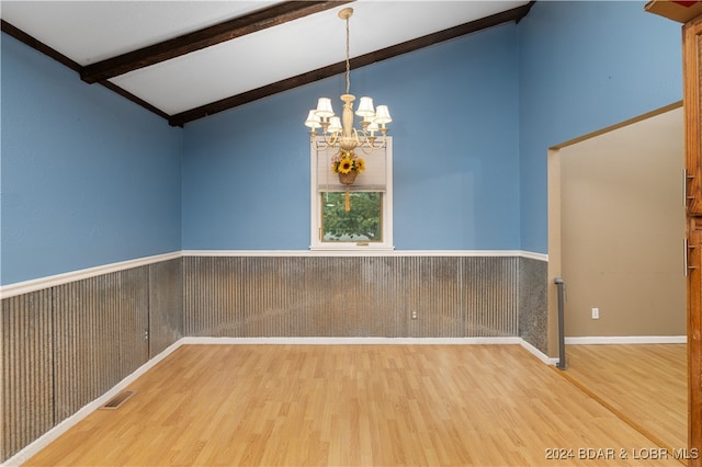 spare room featuring beamed ceiling, wooden walls, hardwood / wood-style flooring, and an inviting chandelier