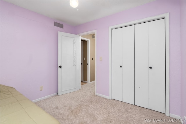 unfurnished bedroom with a closet and light colored carpet