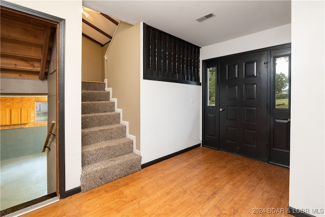 foyer featuring hardwood / wood-style floors, vaulted ceiling, and a textured ceiling